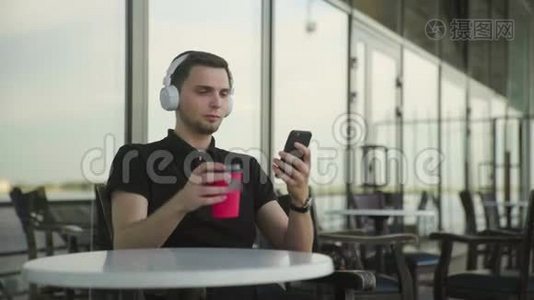 有耳机、有电话的帅哥坐在咖啡馆里视频