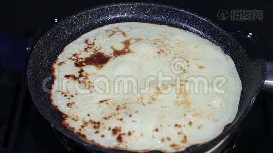 厨师正在黑锅里煎一个金黄可口的薄煎饼，锅里煮着，蒸着植物油视频
