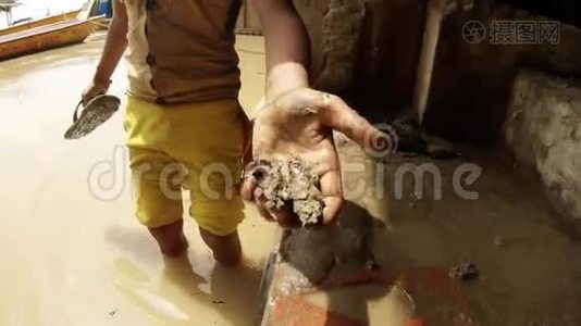 小印度男孩手里拿着泥巴洗着拖鞋把椰子从脏水里扔出来，把牛船扔到码头上视频