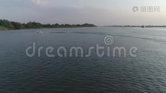运动员在摩托艇后的尾板上冲浪的航拍镜头，水沿着河流缓慢地流动视频