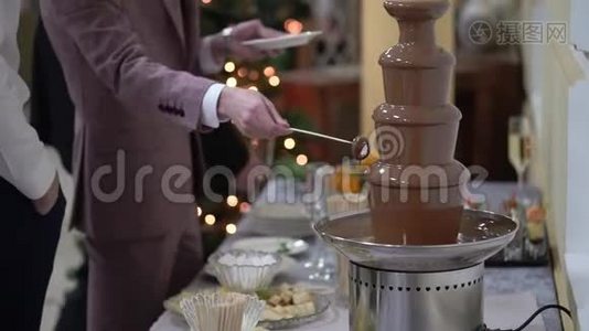 将水果倒入液体巧克力喷泉火锅中视频