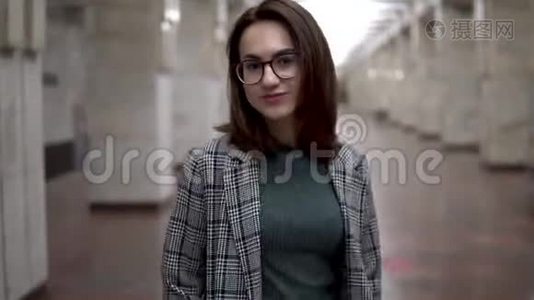 一个年轻的女人在地铁里接近火车。 一个穿外套戴眼镜的女孩视频