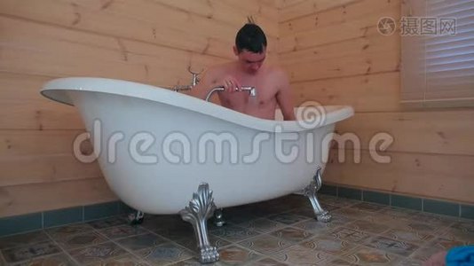 一个男人坐在浴室里洗澡。视频
