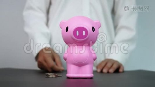 女人把硬币放进房间里的粉红色储蓄罐里。 省钱的概念。视频