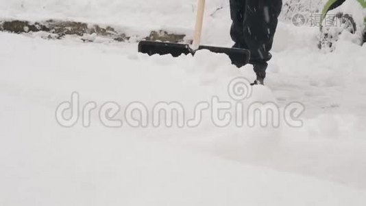 一个拿着铲子的人在一夜暴风雪后清除了汽车周围的积雪。视频