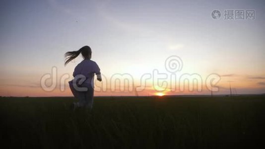 日落时分，小女孩正在草地上奔跑。 童年梦想的概念或前进的愿望。视频