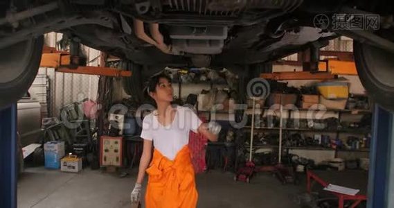 年轻漂亮的汽车修理工在车库里检查汽车底盘。视频
