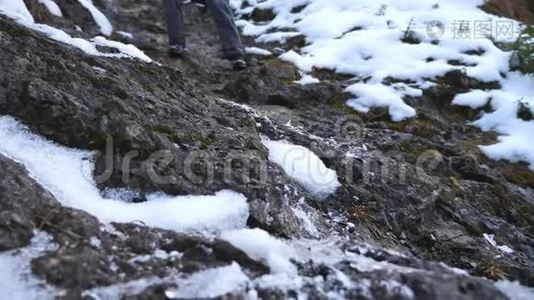 年轻徒步旅行者的脚在旅行中沿着岩石斜坡行走。 男游客的腿下了雪山。 健康视频
