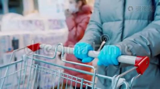 穿着蓝色橡胶手套的女人正在超市推一辆手推车。 把手举起来。视频