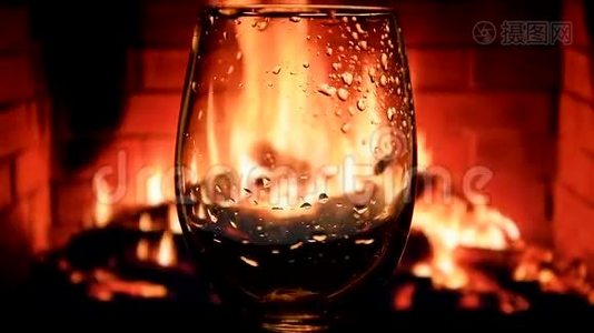 在壁炉背景下缓慢地将白葡萄酒从瓶子倒入酒杯中，葡萄酒的美丽库存镜头视频