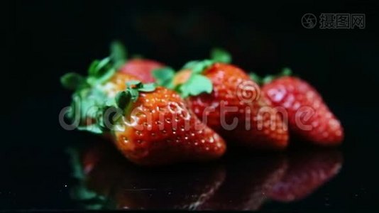 特写镜头集中在一组新鲜、成熟、多汁的红色草莓上，放在黑色上视频