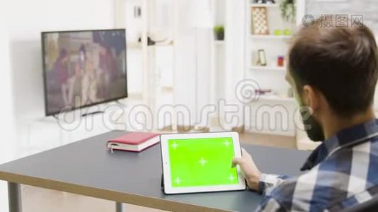 在明亮的客厅里用绿色屏幕滚动数字平板电脑视频