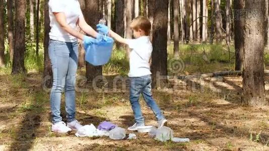 一个小男孩在树林里收集垃圾，和他的母亲一起放进一个袋子里。 家庭活动家关心大自然视频