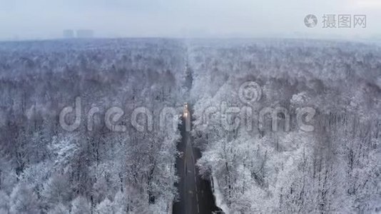 一条穿越冬天、白雪覆盖的森林的公路的无人视野视频