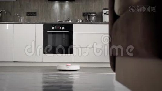 在时尚的现代厨房里打扫卫生。 自动机器人吸尘器沿着其轨迹移动。 a的要素视频