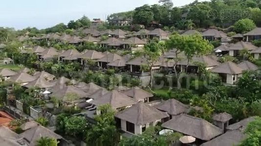 一架无人机飞过海滨的一个热带小屋村庄。视频