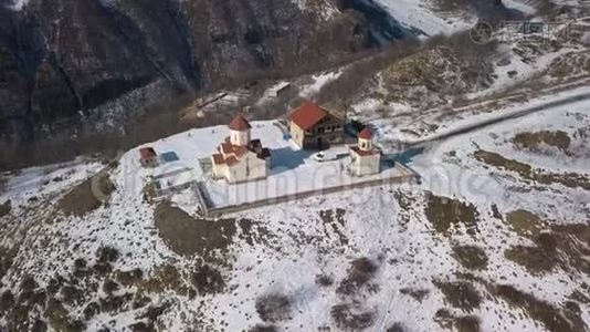 在山上的一座教堂上空盘旋，俯瞰着一座雪山峡谷视频