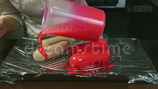 特写女人的双手在四种冷冻的椭圆形蛋糕上倒入粉红色液体釉视频