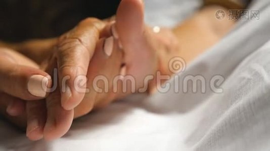女人温柔地抚摸着母亲照顾她的手。 女儿安慰老妈妈皱着胳膊躺在床上视频