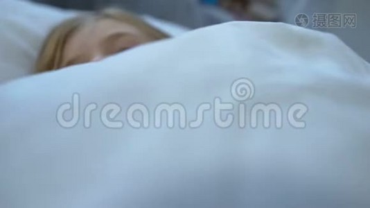 戴着围巾的小金发女孩睡在床上，感觉不舒服，感染了流感病毒视频
