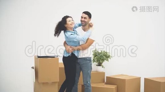 年轻夫妇正一起搬到一间新公寓。 拥抱和依偎的一对。 他们注意到箱子上有一些文件视频