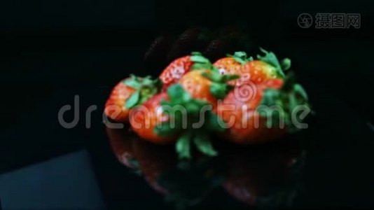 把注意力集中在一堆新鲜多汁的红色草莓上，放在黑色的背景上视频