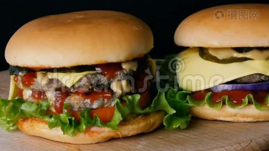 两个多汁的脂肪汉堡或芝士汉堡，番茄酱和芥末酱流在一起，生菜肉切块和黄瓜视频