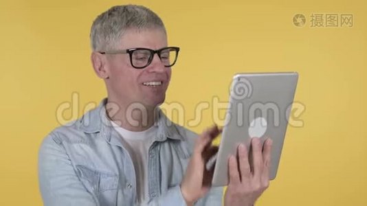黄色背景下的临时老人通过平板进行视频聊天视频
