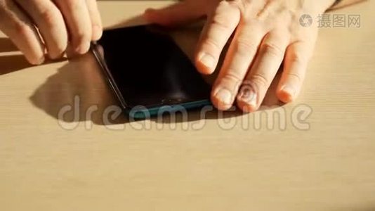 男人`手从智能手机屏幕上取出保护膜。视频