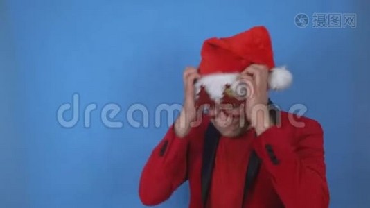 穿着圣诞老人服装的年轻人抱着他的头，在蓝色背景上摇头，复制空间视频