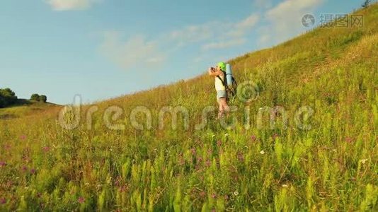 女徒步旅行者在山上，背着一个背包和望远镜在电话中拍摄大自然。视频