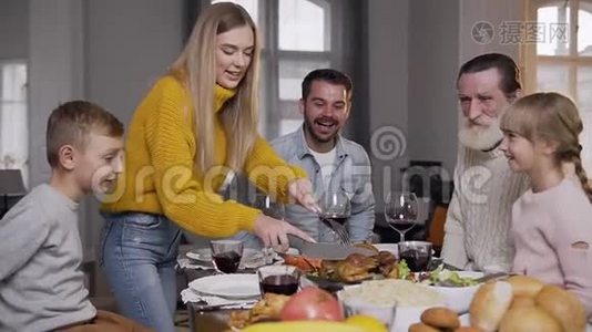 在家庭节日晚餐时，穿着针织毛衣雕刻烤火鸡的微笑的女人视频