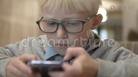 那个戴眼镜的男孩仔细地看着手机屏幕视频