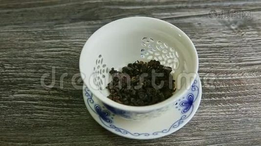 在白瓷茶壶里用干茶叶灌上热水视频