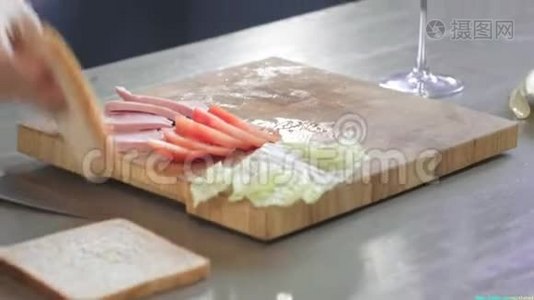 女人在厨房的木板上用刀把俱乐部三明治切成两半，在家里做快餐，厨师是视频
