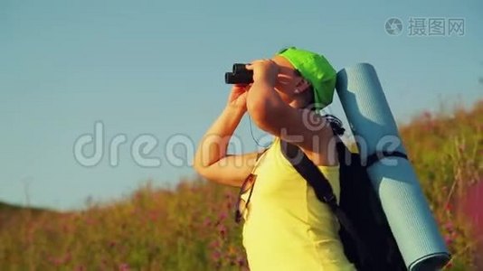 女徒步旅行者在一座小山上，背着一个背包，用望远镜看风景视频