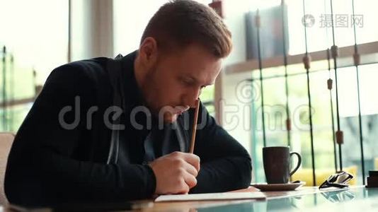 年轻男子写蓝图的肖像，坐在舒适的咖啡馆里的桌子旁视频