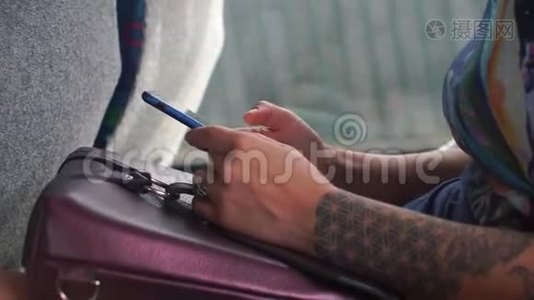 手臂上有纹身的女孩在公共交通工具中使用智能手机视频
