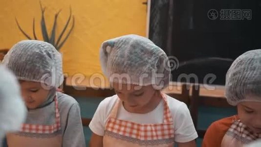 在烹饪学校的烹饪课上，孩子们戴着一次性帽子和围裙做面团。 快乐的孩子们准备面团视频