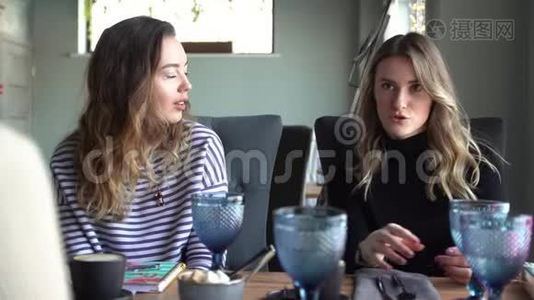 快乐的女性朋友在咖啡馆聊天。 两个美丽的年轻女人闲聊和喝咖啡。 友谊概念视频