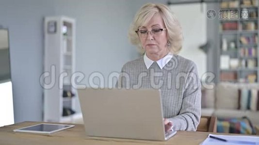 现代办公室使用笔记本电脑的严肃老妇人视频