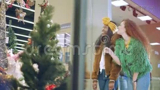 女孩们在商场里看商店橱窗，上面有节日装饰。视频