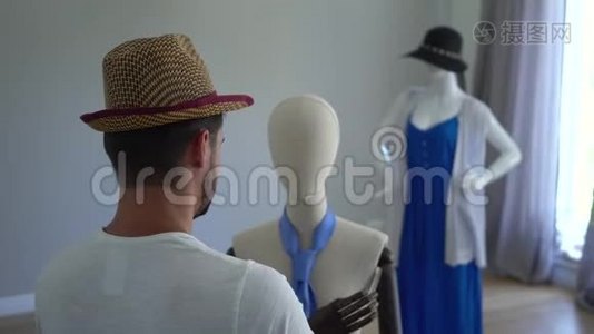 一个年轻人把帽子戴在人体模型的头上。 在缝纫室或视频