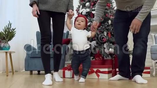 一张漂亮的家庭照片，手牵着他们甜蜜的婴儿，和他一起在装饰的房间里散步。视频