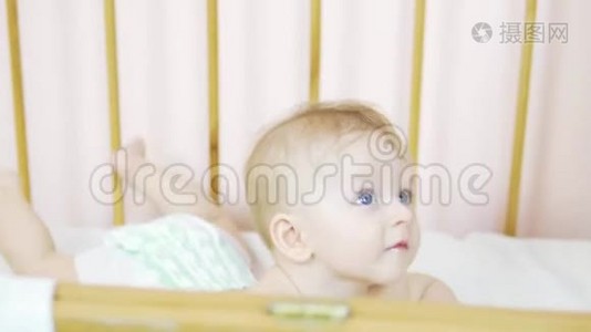 一个迷人的蓝眼睛新生儿躺在婴儿床上，看着相机。视频