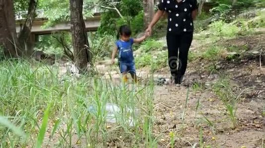 亚洲小孩和妈妈正在捡起漂浮在河岸上的塑料垃圾。 环境保护概念视频