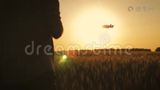 日落时分，一个农民在麦田里使用无人机的剪影。 增加概念技术创新视频