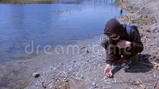 男孩牵着小青蛙，让她走进河里。视频