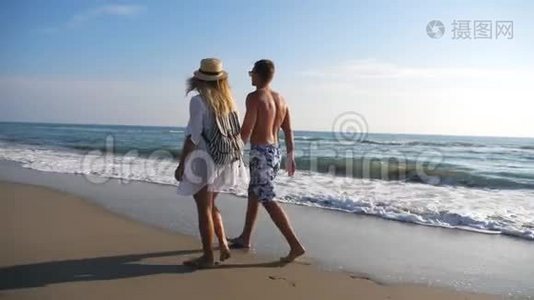在度假胜地休息时，一对情侣牵着手在海岸散步。 男人和女人在海滩上漫步，享受视频