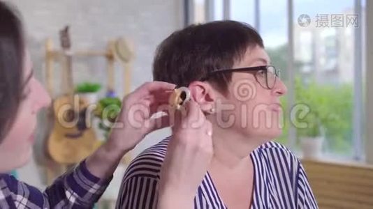 年轻女子帮助在一个听力困难的女子的耳朵上贴助听器视频